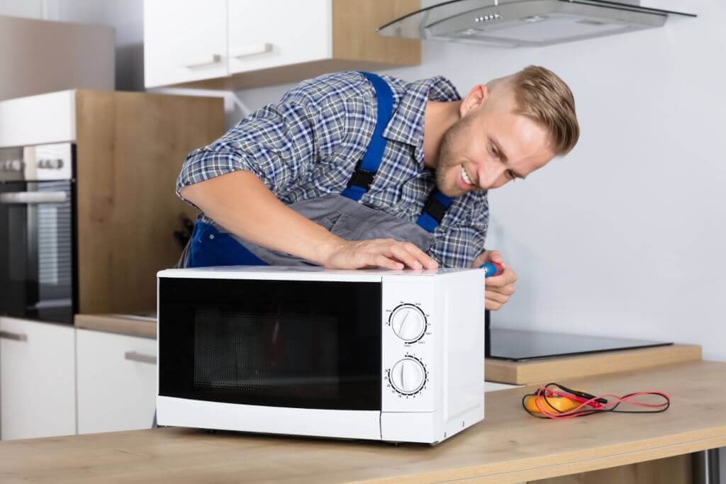 Appliance repair technician fixing the microwave
